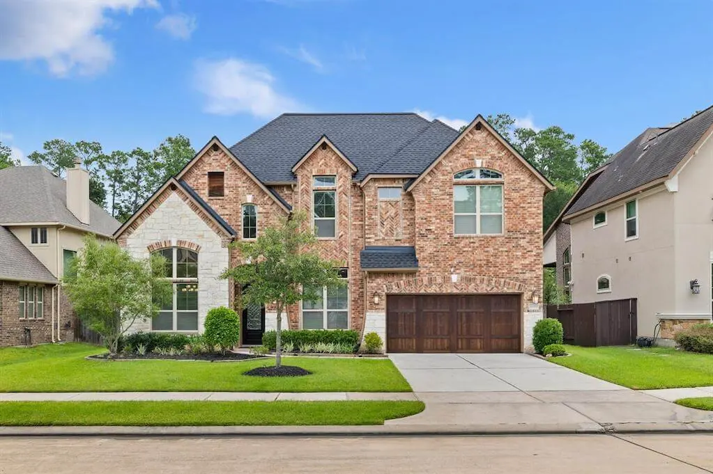 A spacious brick home featuring a driveway and attached garage