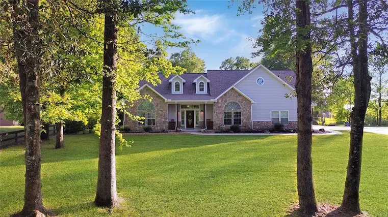 A spacious home surrounded by a large yard and mature trees