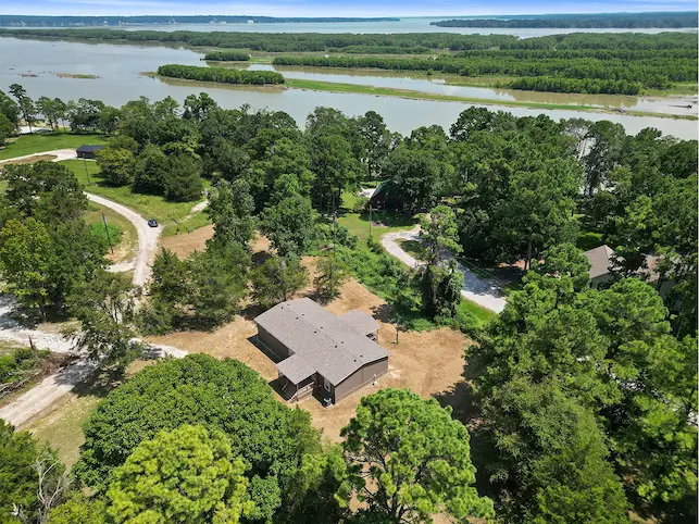 Aerial view showcasing a charming house nestled beside a serene lake, perfect for tranquil living and outdoor activities.