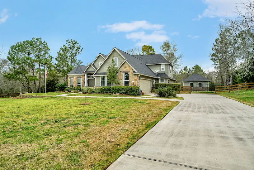A spacious home featuring a long driveway and a well-maintained grassy lawn