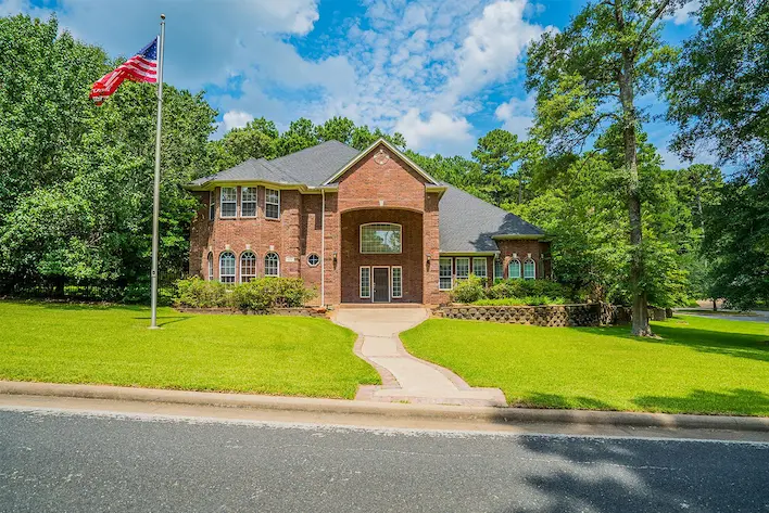 A large brick home with an American flag in the front yard
