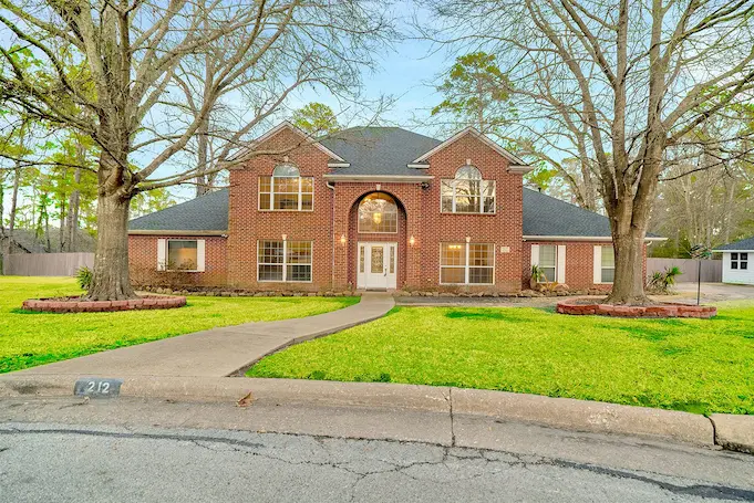 A brick home with a driveway and trees