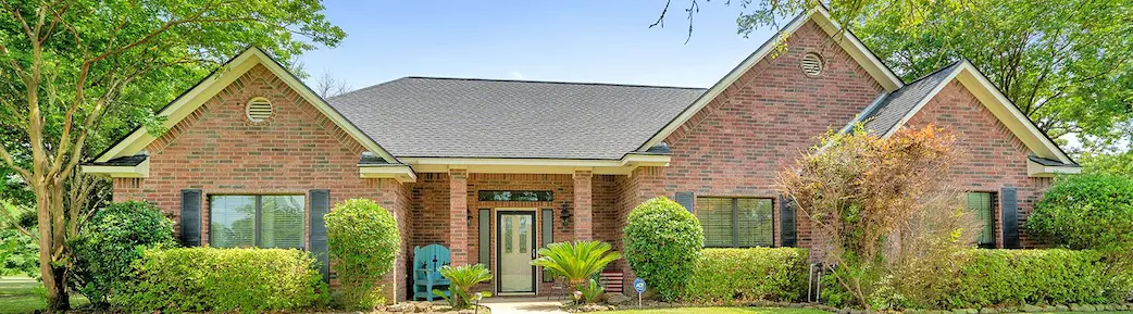 A charming brick home surrounded by a spacious yard and mature trees