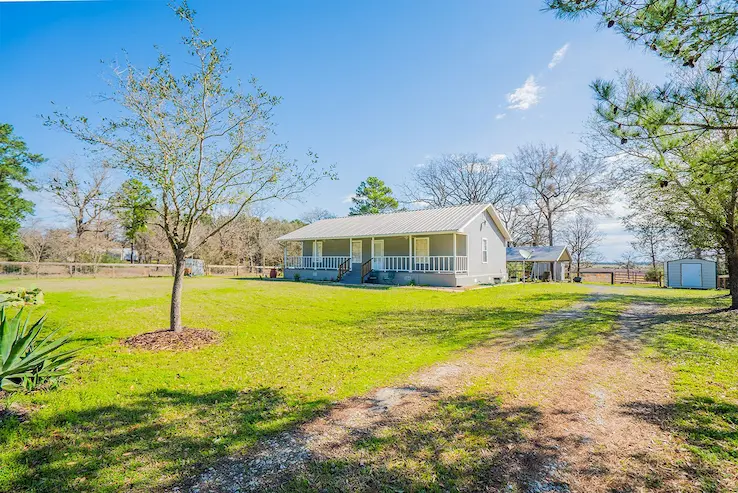 A charming country home with a long driveway surrounded by lush trees