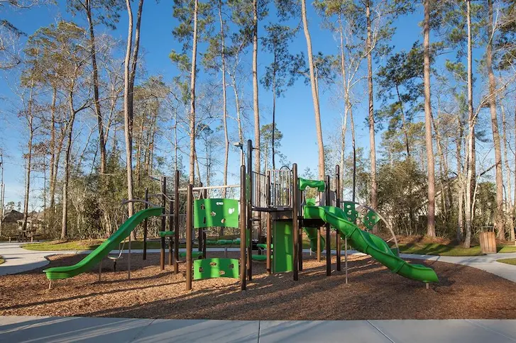 A vibrant playground featuring green slides and swings, perfect for family fun and outdoor activities.