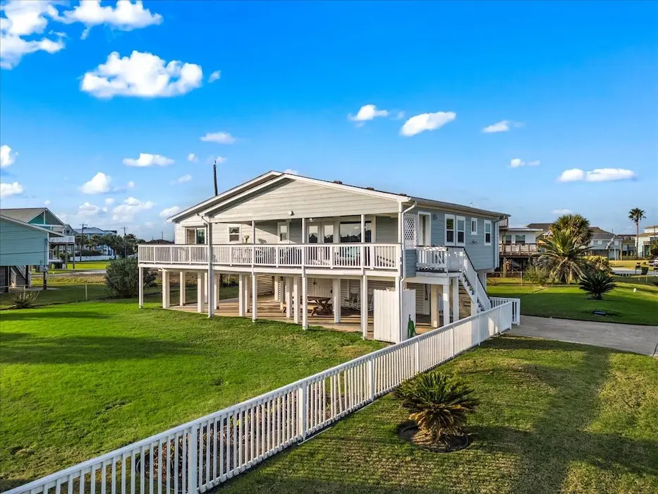 A spacious home featuring a large deck and a lush grassy yard, perfect for outdoor gatherings and relaxation.