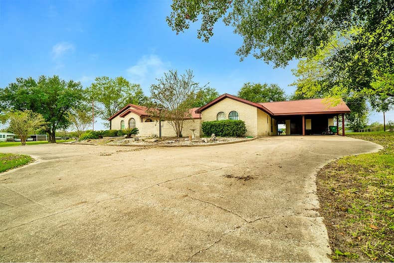 A spacious home featuring a long driveway and lush trees
