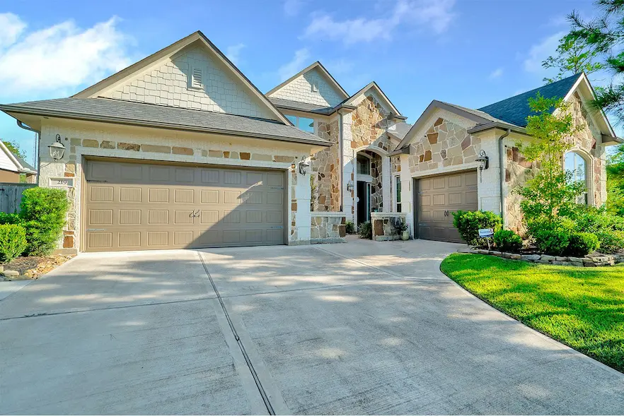 Spacious home featuring two garages and a wide driveway, perfect for accommodating multiple vehicles and enhancing curb appeal.