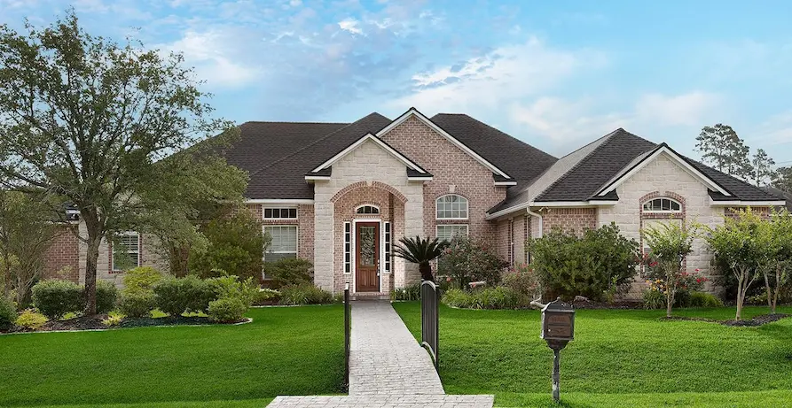 A large brick home with a driveway and lawn