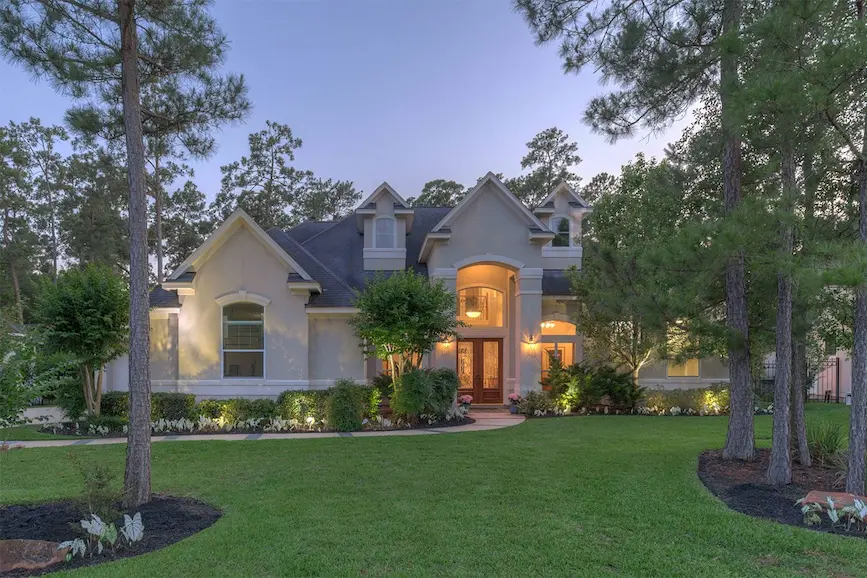 A large home with landscaped front yard and trees