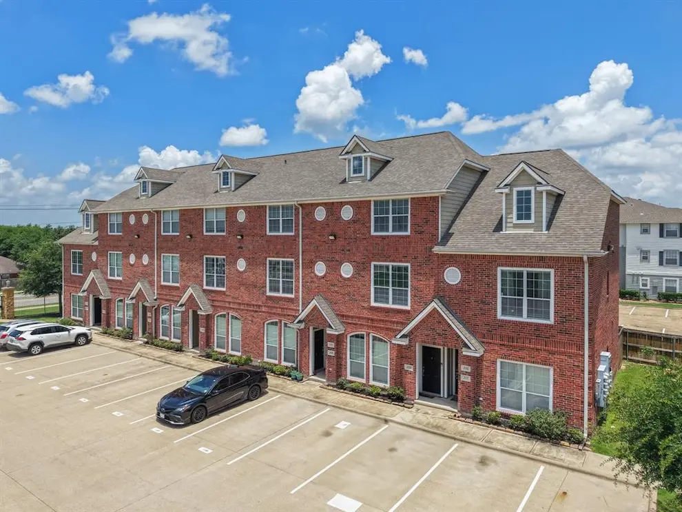 Modern apartment complex situated at the edge of a spacious parking lot