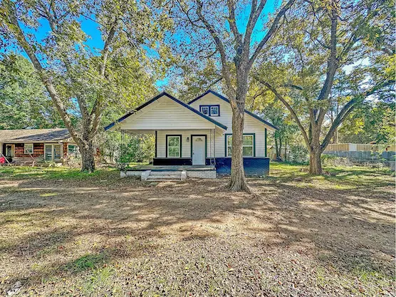 A charming small house featuring white siding and elegant black trim
