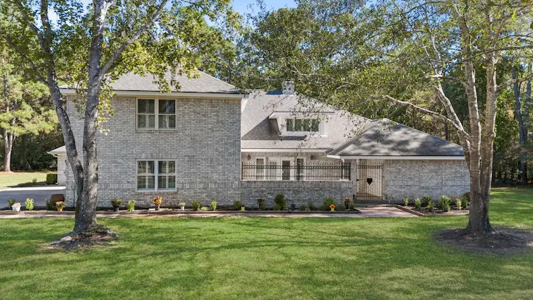 A spacious home surrounded by a large yard and mature trees