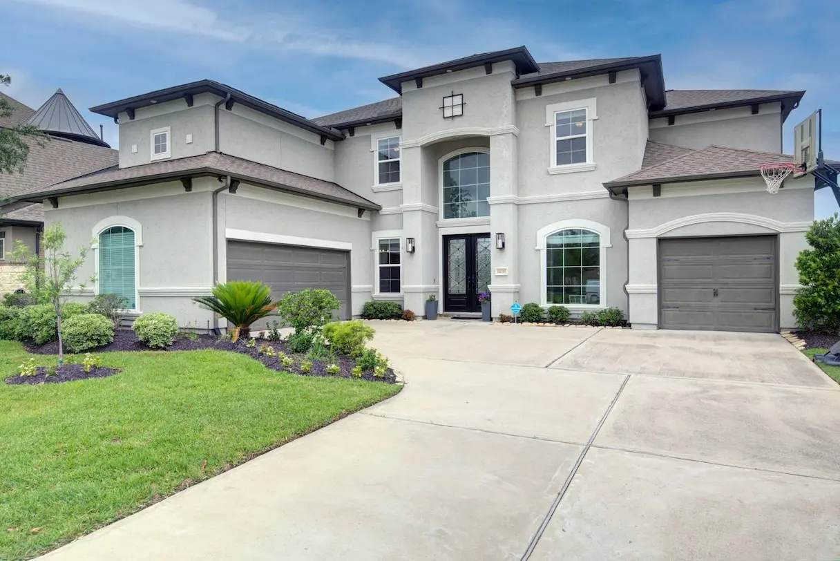 A large home featuring a spacious driveway and well-maintained landscaping, ideal for potential buyers.