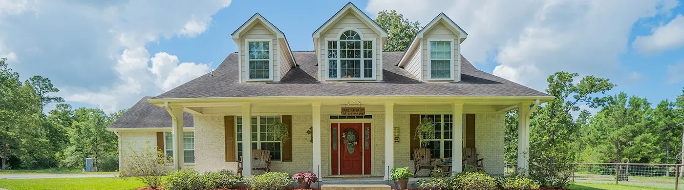 Charming white house featuring a welcoming red door and a spacious porch, perfect for enjoying outdoor moments with family.