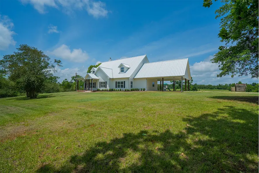 A charming white house surrounded by a spacious yard and mature trees