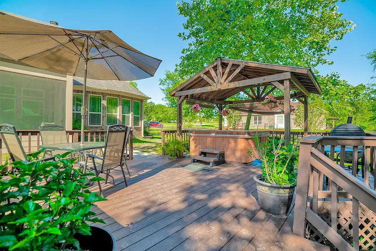 A wooden deck featuring a hot tub and a large umbrella