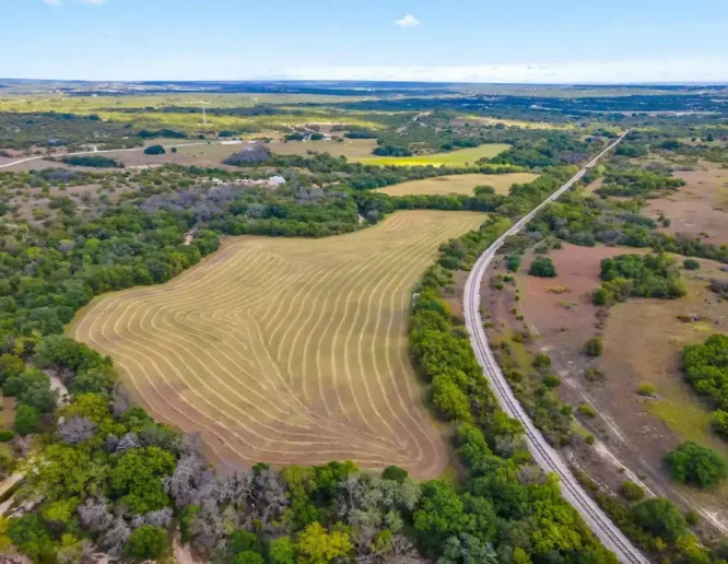 Aerial view showcasing a sprawling ranch with fields and a winding road