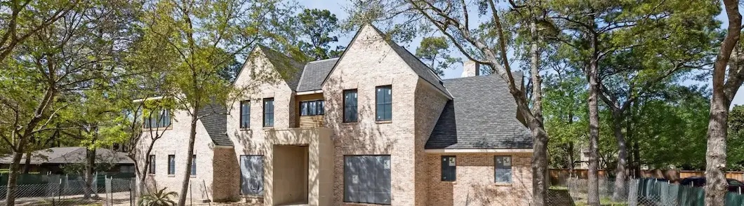 A house featuring a prominent stone facade and a fence