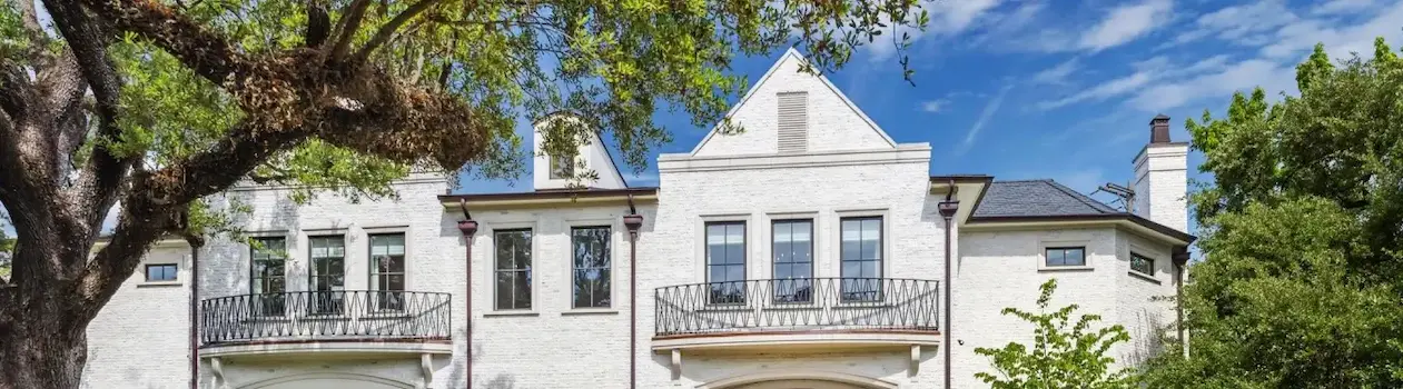 A white house with a large front porch and a tree