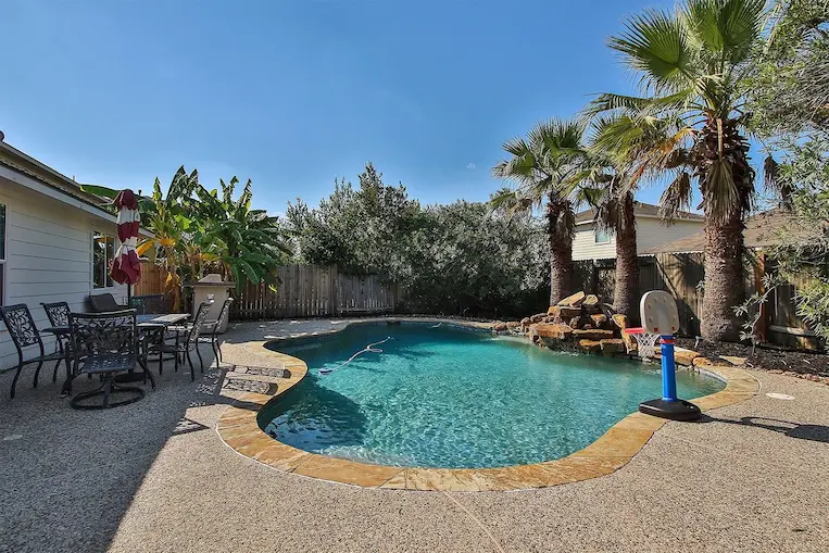 A spacious backyard featuring a pool and stylish patio furniture, perfect for outdoor relaxation and entertaining.