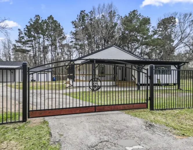 A charming home featuring a decorative gate and a sturdy fence
