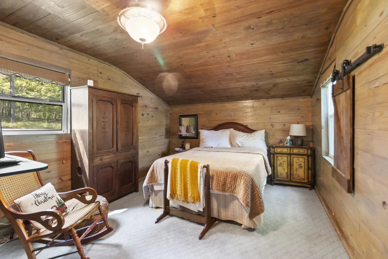 Cozy cabin bedroom featuring a comfortable bed, a chair, and a dresser