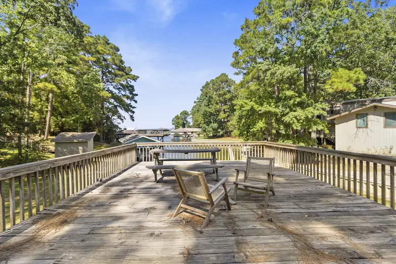 A deck featuring chairs and a table, providing a scenic view of the water