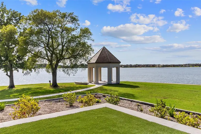 A charming gazebo on lush grass beside a serene lake