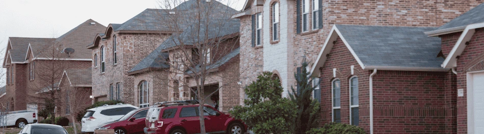 A red car parked in front of a row of charming houses, showcasing the neighborhood's inviting atmosphere and curb appeal.