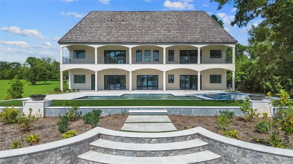 A spacious home featuring a pool with elegant steps leading down to it