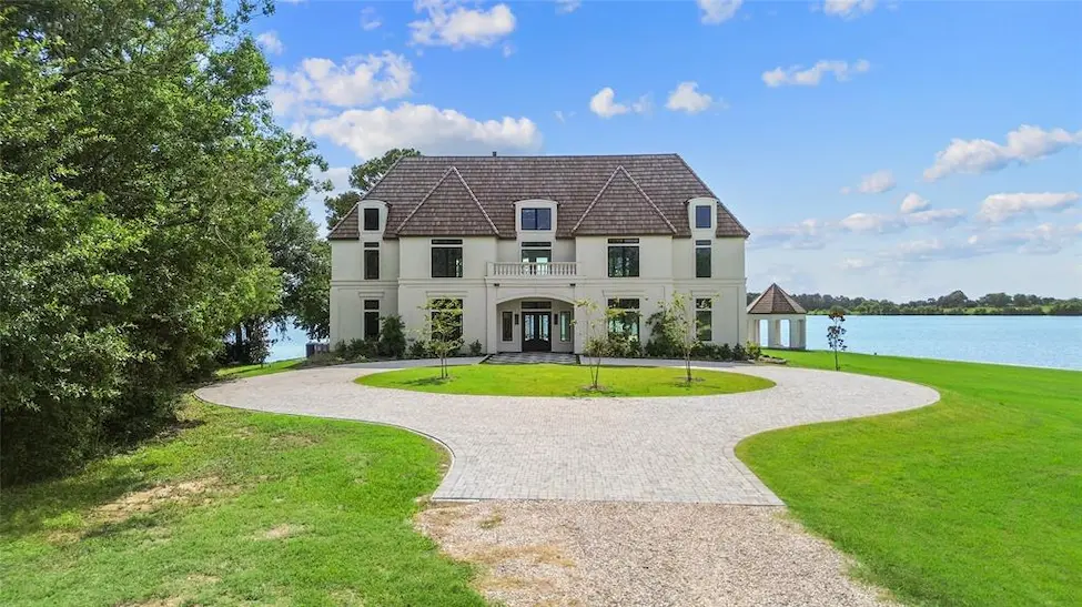 A spacious house with a long driveway leading directly to the water