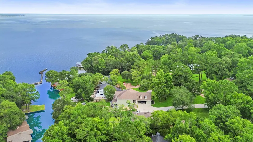 Aerial view of a spacious home nestled among lush trees, showcasing its serene surroundings and ample outdoor space.