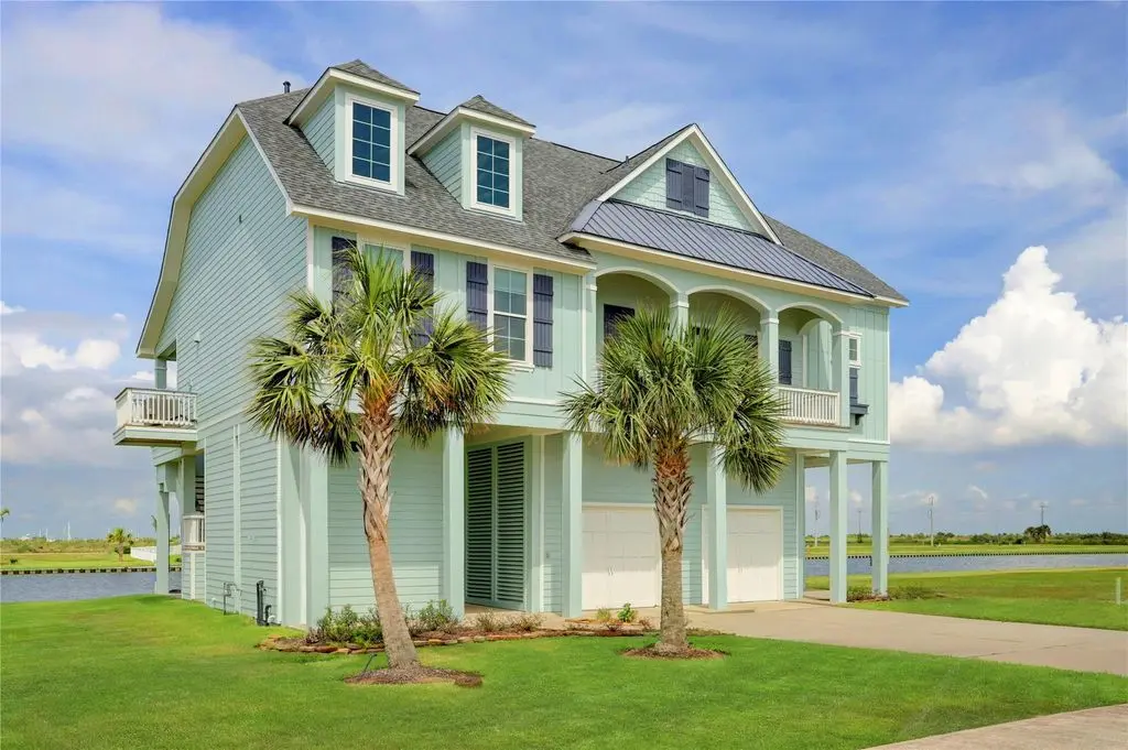 A spacious house surrounded by palm trees, featuring a serene pond in the front yard