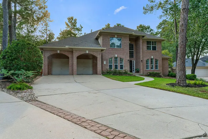 A large brick home with a driveway and trees