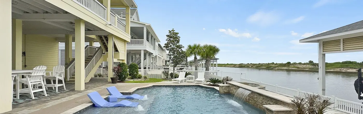 A serene pool and patio area featuring comfortable chairs and tables