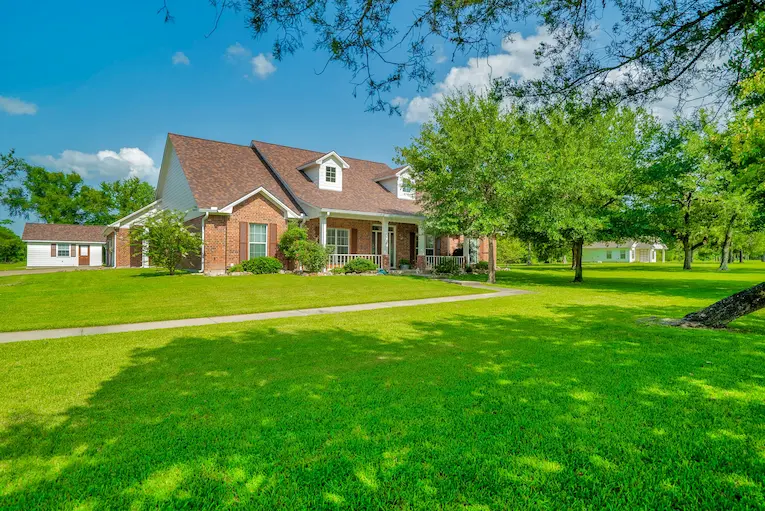 A spacious brick house surrounded by a large, well-maintained yard, ideal for outdoor activities and gatherings.