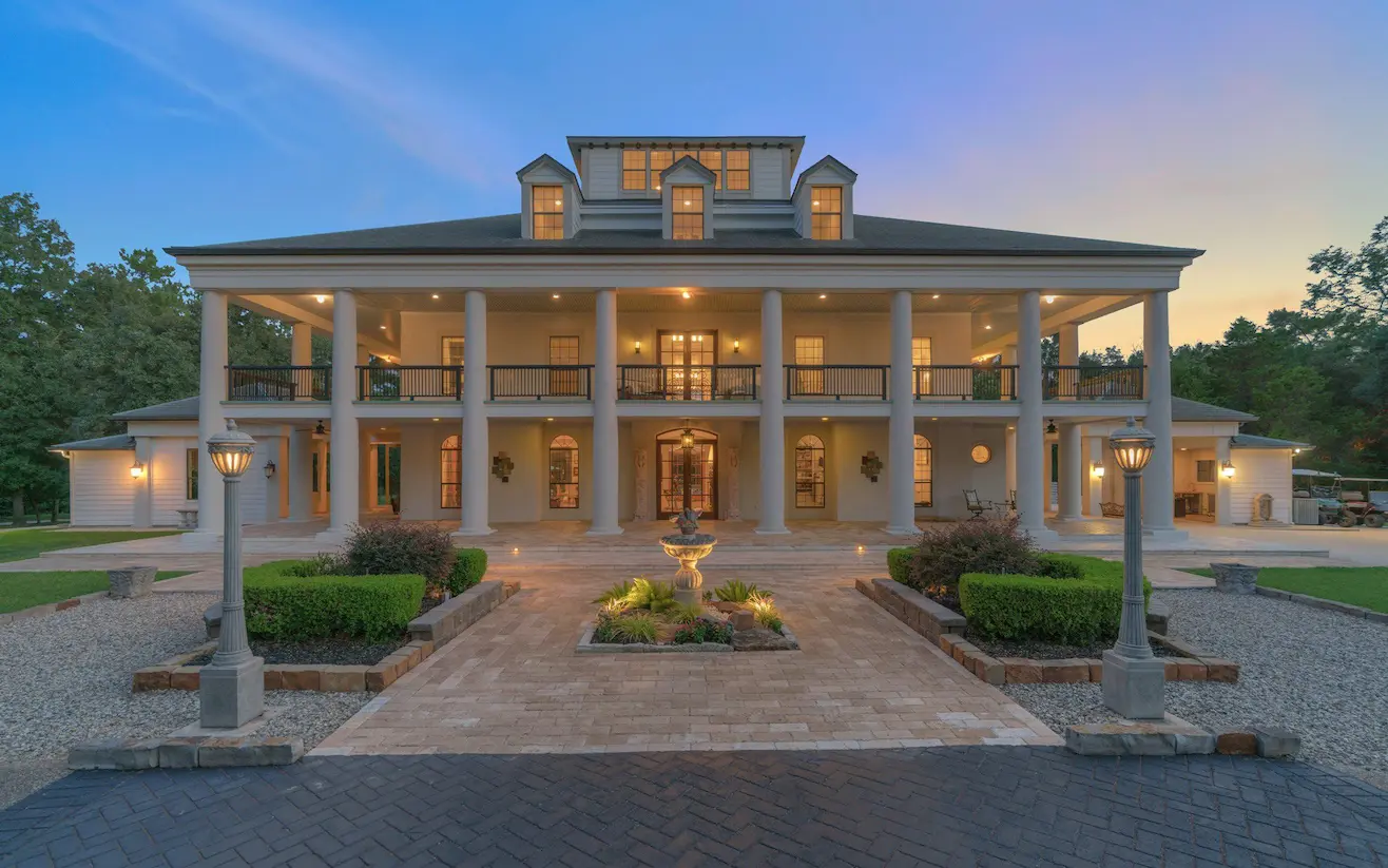 A spacious home featuring a large driveway and an inviting front porch